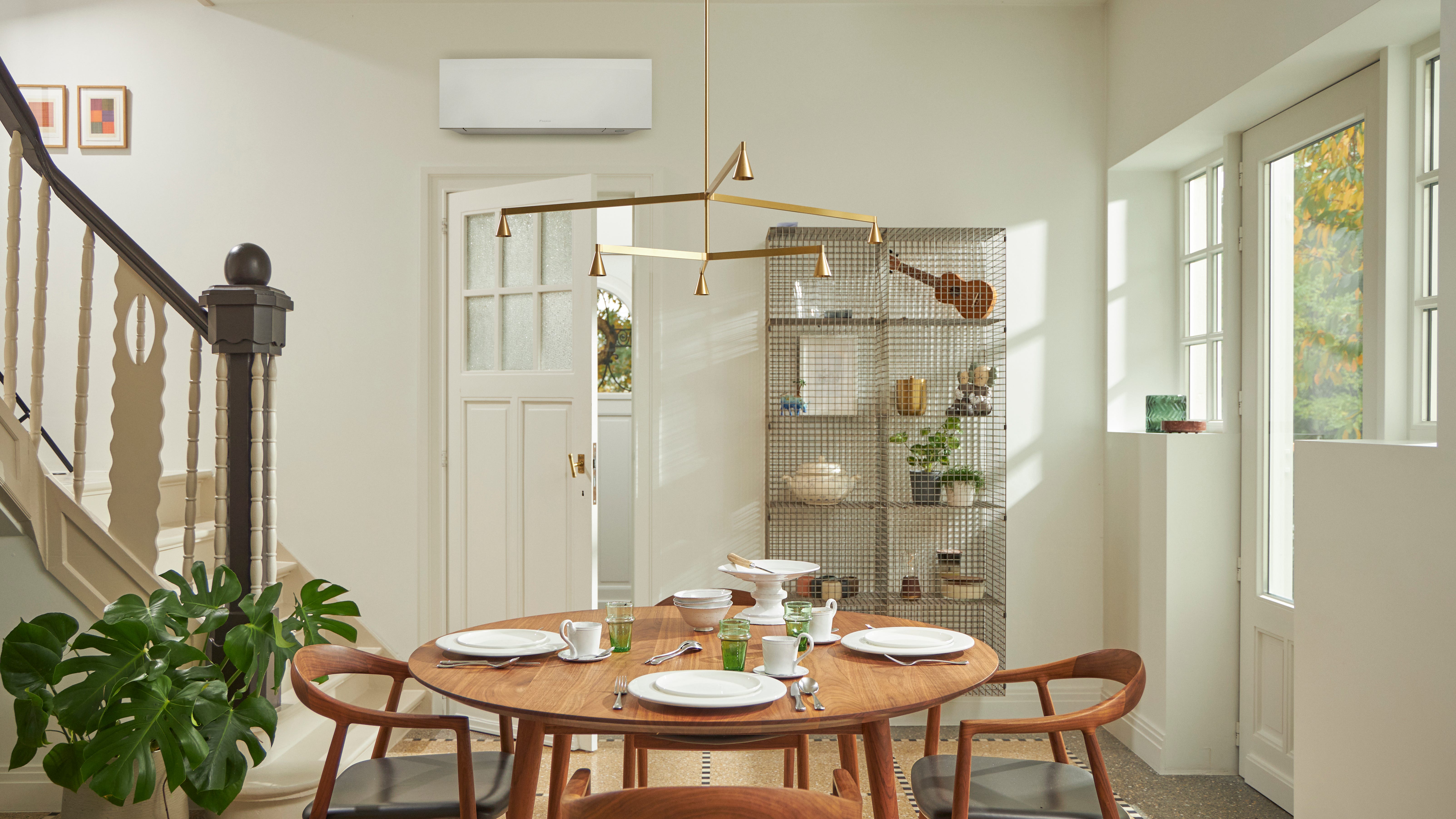 Pokoj s velkým oknem, dřevěným stolem a černou nástěnnou klimatizací